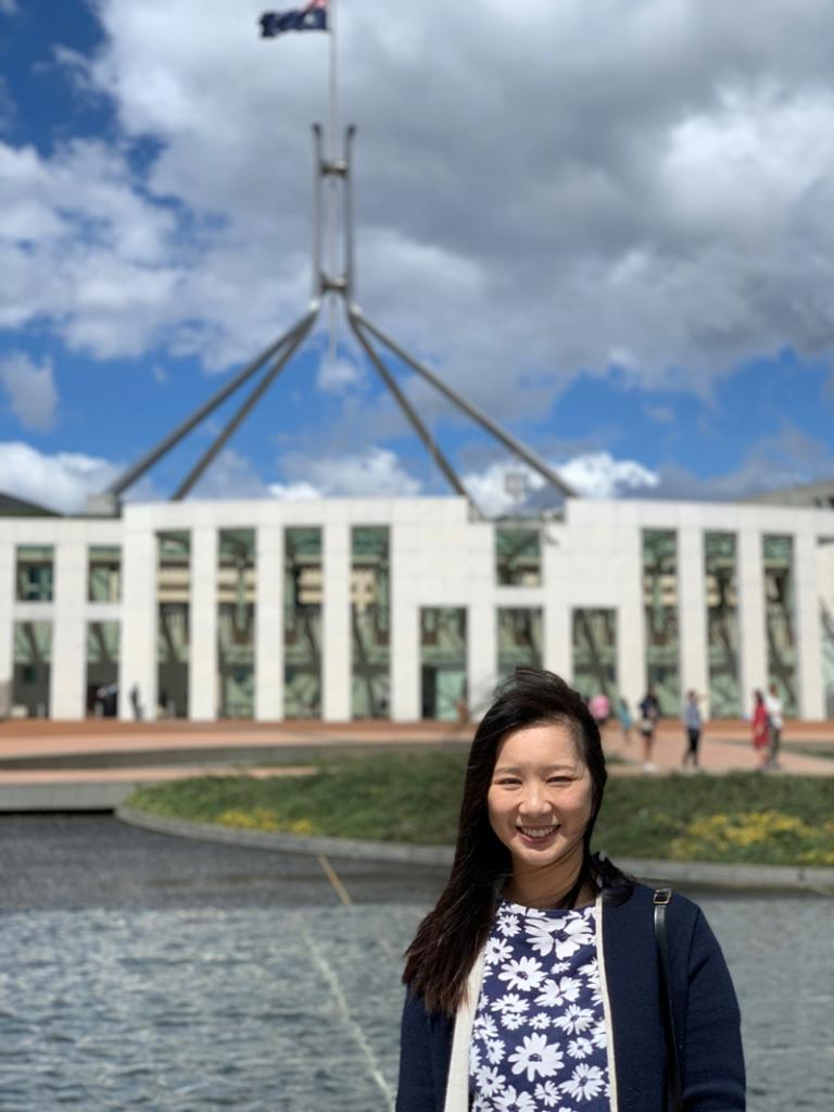 A woman in casual attire stands out the front of Parliament House in Canberra on a sunny day.