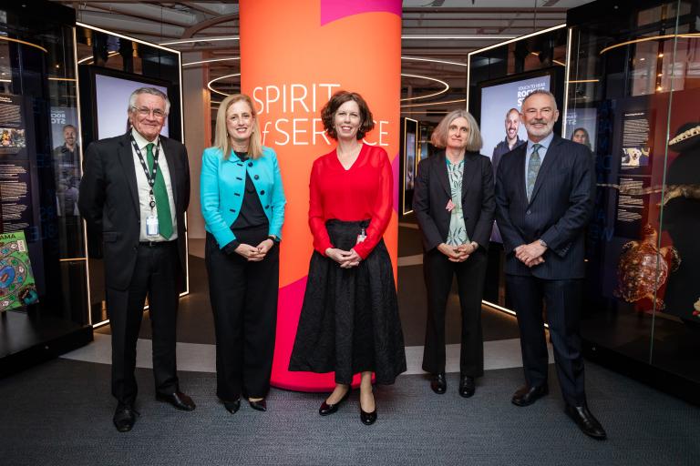 Four people stand in front of a sign that reads Spirit of Service.