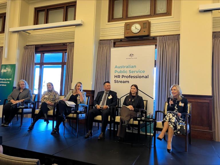 Six people sitting on a panel with microphones, in front of a banner that says Australian Public Service HR Professional Stream.