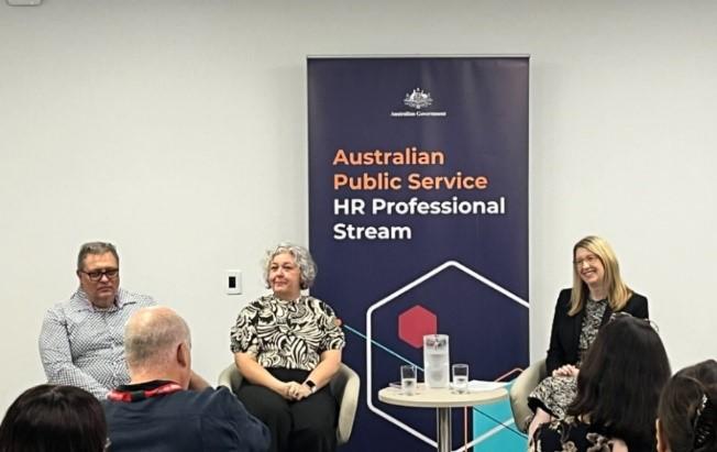 An audience watching three people on a panel.