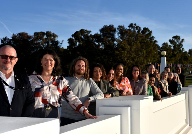 A photograph of 16 Collaboration Circle members standing in a line, facing the camera and smiling outside of Old Parliament House in Canberra.