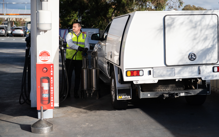 A photograph of a trade measurement officer from the National Measurement Institute testing petrol at a service station. 