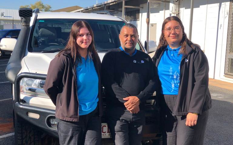 A photograph of 3 Remote Service Officers from Services Australia, standing in front of their 4WD work vehicle and smiling.  