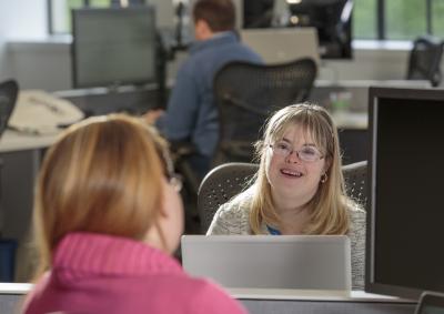 Young woman with Down Sydnrome working at her laptop in an office