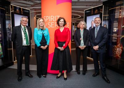 Four people stand in front of a sign that reads Spirit of Service.