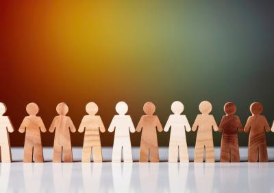 Wooden people holding hands against a colouful background