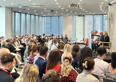 The back of an audience watching four people on a panel.