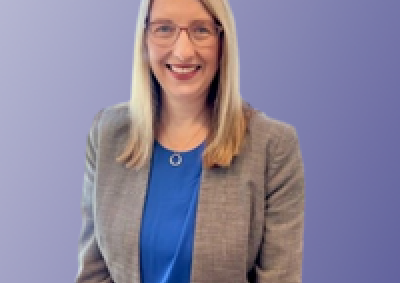 picture of Alison Stott, a woman standing in front of a purple background smiling
