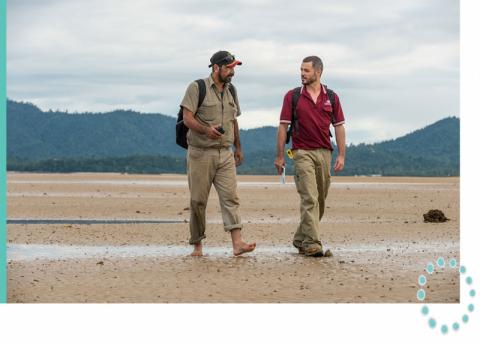 Two rangers walking over a sandy beach