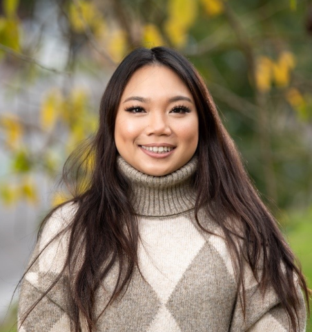 Organ donor recipient Kristy pictured in an outdoor setting in front of a tree with yellow and green leaves, smiling at the camera.